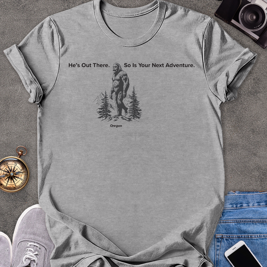 He's Out There. So Is Your Next Adventure - Oregon | Unisex Softstyle T-Shirt | Oregon Bigfoot Travel Tee