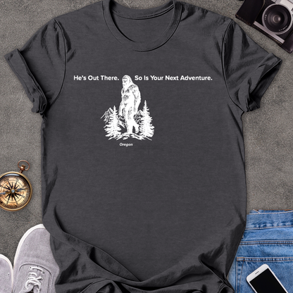 He's Out There. So Is Your Next Adventure - Oregon | Unisex Softstyle T-Shirt | Oregon Bigfoot Travel Tee